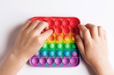 Beyaz arka planda bir çocuğun elinde renkli popit anti-stres oyuncağı
