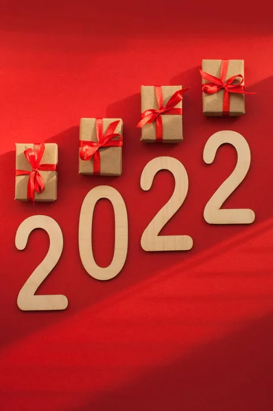 红色缎带工艺包装中的礼品和红色背景上的编号2022 阴影中带有垂直格式的文本空间 — 图库照片