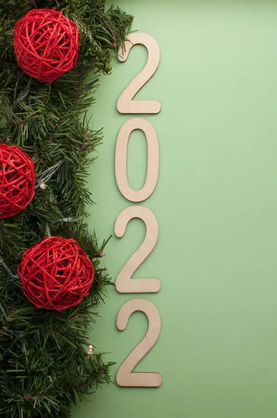 2022年的数字 绿色背景 圣诞树枝条和红球组成的花环旁边 — 图库照片
