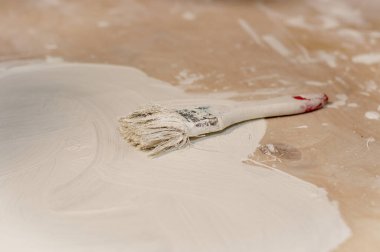 Ahşap bir yüzeyin arka planına beyaz boya sürülmüş bir fırça.