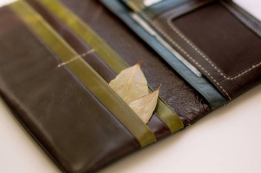 İçinde defne yaprakları olan açık deri bir cüzdan, para muskası gibi.