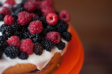 Üzerinde ahududu ve böğürtlen olan ev yapımı kek.