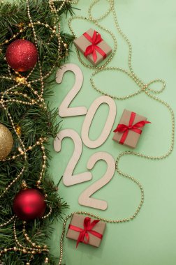 2022 sayıları, şenlikli dekor ve köknar dallarının yanında yeşil bir arkaplanda.