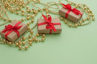 Kırmızı kurdeleli el işi kağıtlar içinde kutular yeşil arka planda altın bir çelenk ve metin için bir yer.