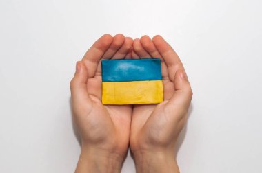 Ukrayna bayrağı beyaz bir arka planda bir çocuğun ellerinde plastikten yapılmıştır.