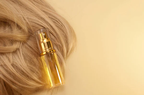 hair oil on blonde hair on beige background with space for text