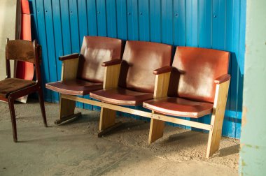 three old leather chairs covered with brown leather, and one chair against a blue wall