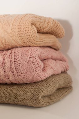 three knitted sweaters in beige and pink colors on a white background