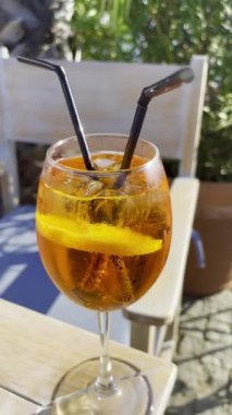 Cocktail Aperol Spritz. Traditional Italian aperitif before dinner. Glass of drink with sea or ocean backdrop