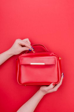 Parlak yaz moda aksesuarları. Kırmızı arka planda kırmızı deri çanta ya da el çantası. Parlak manikür torbalı kadın elleri. Üst Manzara. Düz Yat.