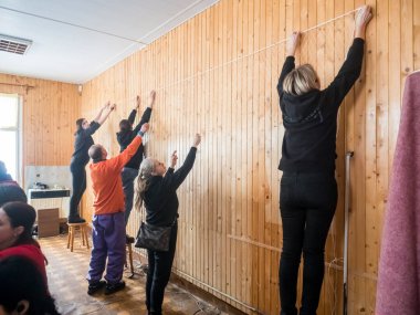 KOSIV, UKRAINE - 5 Mart 2022 Bir grup gönüllü Ukrayna ordusu için bir insani yardım merkezinde kamuflaj ağı örüyor