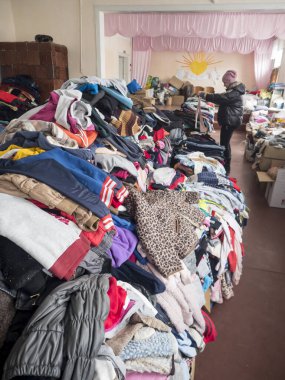 KOSIV, UKRAINE - 5 Mart 2022 Rusya 'nın Ukrayna' ya karşı savaşı. Ukraynalı mülteciler için insani yardım. Yerlerinden edilmiş insanlar için tasnif merkezinde kalın giysiler ve ayakkabılar.