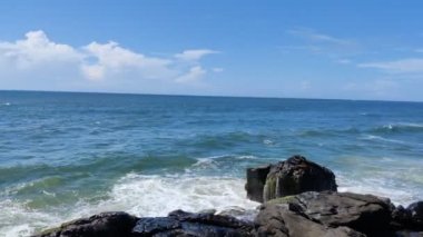 Güneşli bir günde mavi gökyüzünün altında deniz kıyısındaki kayalara vuran dalgaların çarpıcı görüntüsü. Bekal Kalesi 'nin turizm merkezinin yanındaki Costal alanında..