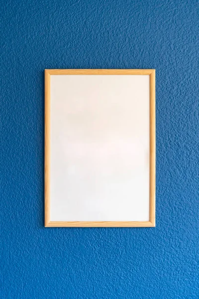Empty wooden frame, poster white blank canvas mock up on a blue wall, living room template front view, interior home accent decor