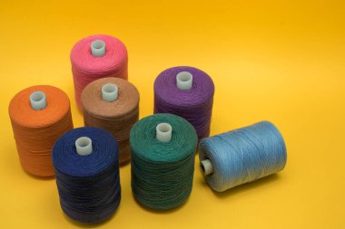 Sarı arka planda çok renkli iplik makaraları. Yukarıdan görüntüle.