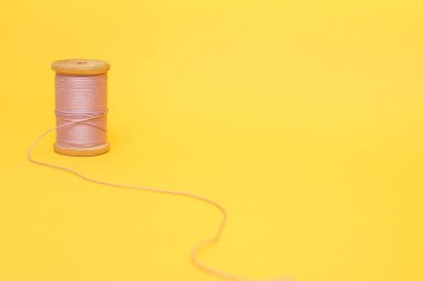 Sarı arka planda pembe bir iplik makarası