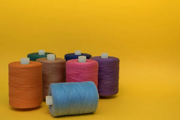 Multicolored spools of thread on a yellow background — Stock Photo, Image