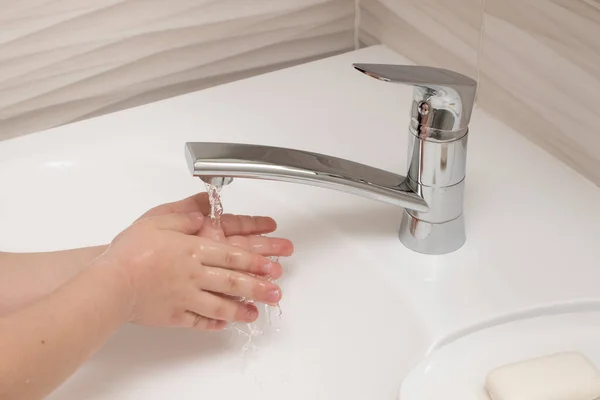 Het kind wast zijn handen onder water — Stockfoto