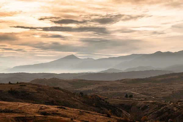 Yanan turuncu gökyüzünün manzarası ve geniş bir dağ zinciri..