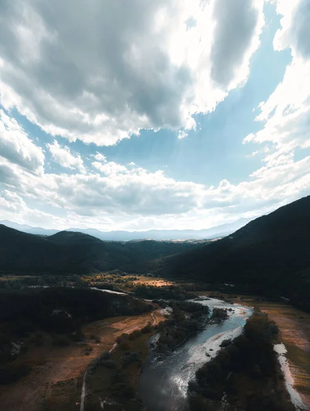 Dağları, bulutları ve nehri olan güzel bir manzara.