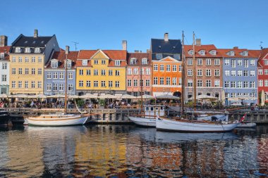 Kopenhag, Danimarka - Eylül 2022: Renkli Geleneksel ev mimarisi ve Nyhavn Limanı 'ndaki kanal dolgusu üzerindeki tekneler
