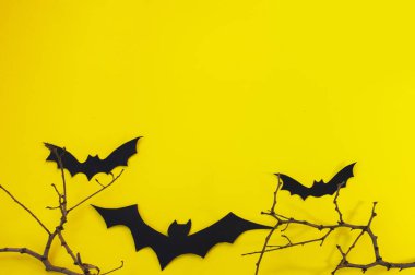 Cadılar Bayramı ve dekorasyon konsepti - yarasalar, balkabakları, kasvetli kağıt ev, sarı arka planda kara ağaç dalları. Katlanmış kağıttan yapılan Origami sanatı. Kesik yarasalar ve diğer dekorasyonlarla Cadılar Bayramı arka planı.