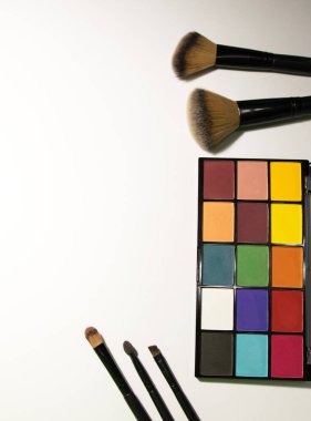 parlak makyaj gözkapağı paleti ve beyaz arka planda makyaj fırçaları makyaj sanatçısı için gölge arkaplan bırakır. Makaleler ve kozmetik reklamları. metin için yer.