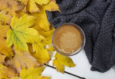 Gri örülü ekose ve sarı sonbahar yapraklı bir fincan sütlü bir fincan kahveyle sonbahar sıcacık hayatı. Metin, yazı ve günlük için yeri olan sonbahar arkaplanı.