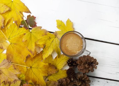 Sonbahar sıcacık hayatı, bir fincan sütlü kahve ve sarı sonbahar yapraklarıyla. Metin, yazı ve günlük için yeri olan sonbahar arkaplanı.