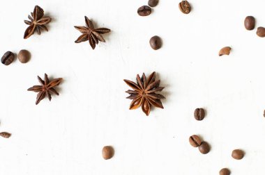 Beyaz arka planda dağınık kahve çekirdekleri ve yıldız anason. Bir çeşit sveru. Düz yat. İlham verici metinler için alan. Kahve zamanı..
