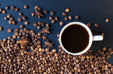 Arka planda koyu kahve ve dağınık kahve taneleri olan bir fincan. Günaydın. Bir çeşit sveru. Düz yat. mesaj için yer. Kahve zamanı..