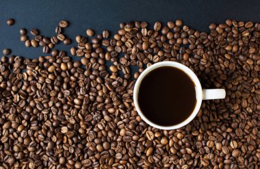 Arka planda koyu kahve ve dağınık kahve taneleri olan bir fincan. Günaydın. Bir çeşit sveru. Düz yat. mesaj için yer. Kahve zamanı..