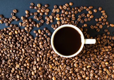 Arka planda koyu kahve ve dağınık kahve taneleri olan bir fincan. Günaydın. Bir çeşit sveru. Düz yat. mesaj için yer. Kahve zamanı..