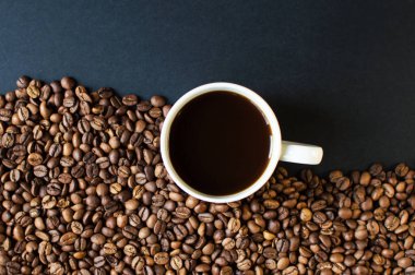 Arka planda koyu kahve ve dağınık kahve taneleri olan bir fincan. Günaydın. Bir çeşit sveru. Düz yat. mesaj için yer. Kahve zamanı..