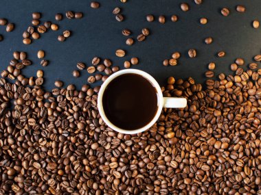 Arka planda koyu kahve ve dağınık kahve taneleri olan bir fincan. Günaydın. Bir çeşit sveru. Düz yat. mesaj için yer. Kahve zamanı..