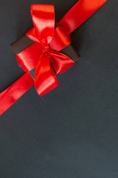 Black Friday - black gift box with a red bow on a dark background. Super sale, sales promotion and special offer. flat lay with place for text. Banner mockup, postcard.