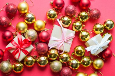 Şenlik konsepti. Kırmızı arka planda fiyonklu bir hediye ve Noel oyuncakları. Yılbaşı, yeni yıl ve tatiller için kompozisyon. metin için yer alan düz uzanma.