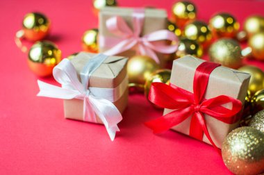 Şenlik konsepti. Kırmızı arka planda fiyonklu bir hediye ve Noel oyuncakları. Yılbaşı, yeni yıl ve tatiller için kompozisyon. metin için yer alan düz uzanma.