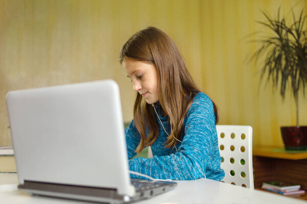 Girl writes down the teacher's assignment in front of her laptop. Online education. Home education