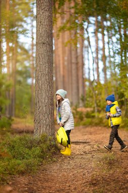Oğlan ve bir kız ormanda dışarıda oynuyorlar. Sonbahar güneşli bir gün.