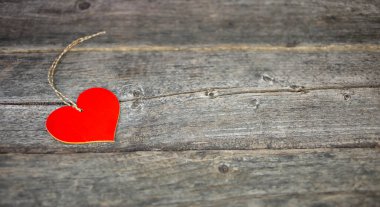 Wooden pendant in the form of a red heart on a wooden background