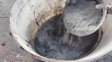 Bir inşaat işçisi kovaya su döktü.