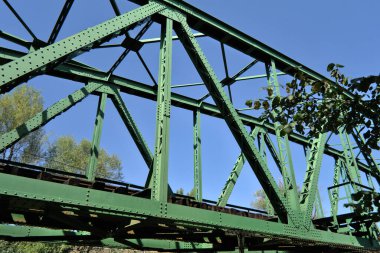 Küçük yeşil demiryolu köprüsünün metal iskeleti, alçak açılı.