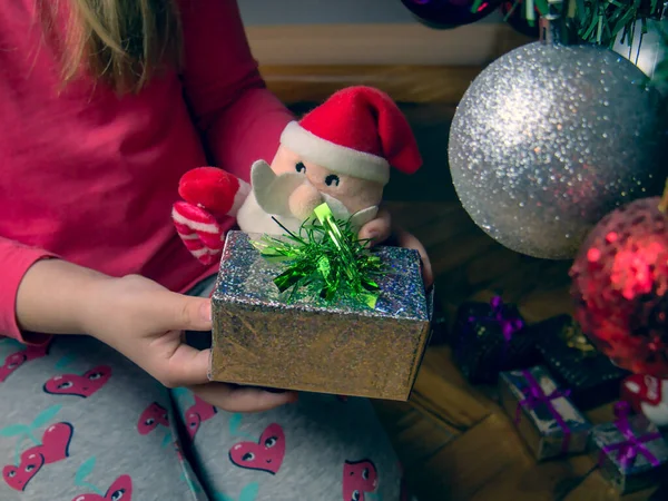 Dziewczyna Siedząca Podłodze Przy Choince Trzymająca Rękach Mały Prezent Świąteczny — Zdjęcie stockowe