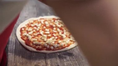 Şef mutfakta pizza hazırlıyor.