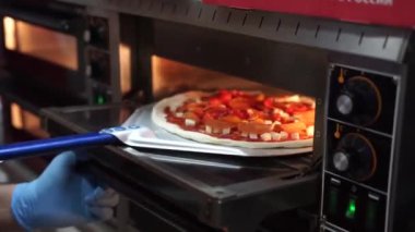Şef mutfakta pizza hazırlıyor.