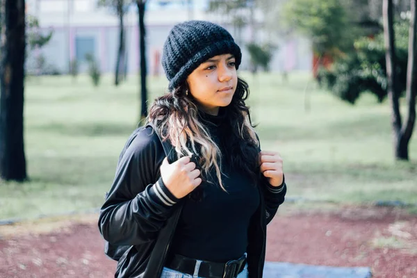 Düşünceli Latin üniversiteli kız parkta yürüyor.