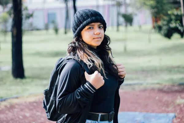 Düşünceli Latin üniversiteli kız parkta yürüyor.