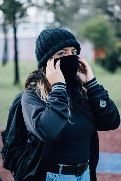 Parktaki Latin üniversiteli kız yüz maskesi takıyor.