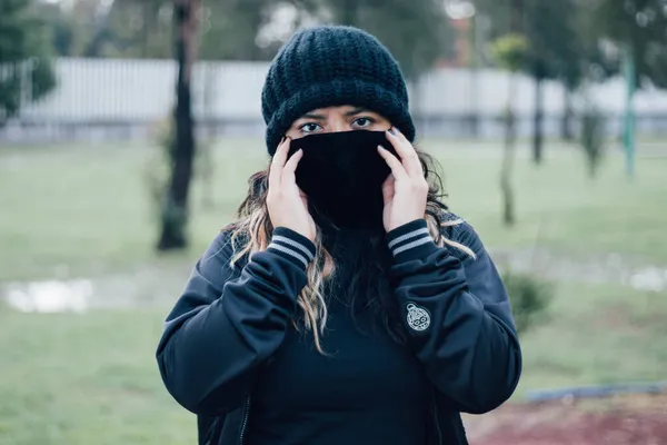 Parktaki Latin üniversiteli kız yüz maskesi takıyor.